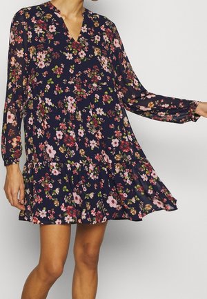Blommönstrad klänning i marinblått med V-ringning, långa ärmar och volangslut. Har rosa och gröna blommönster på lättviktsmaterial.