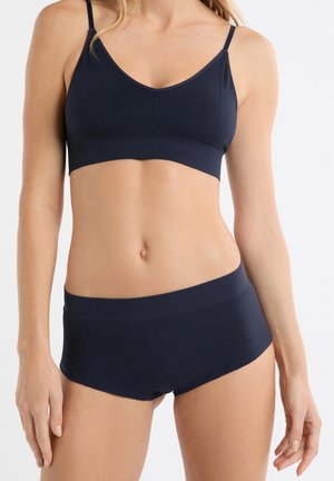 Completo intimo blu navy, reggiseno e shorts senza cuciture con trama a coste, spalline regolabili e fascia larga in vita sugli shorts, progettato per comfort e sostegno.