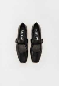 Chaussures en cuir noir avec un design à bout carré, présentant une sangle à boucle proéminente sur le cou-de-pied et une texture lisse. Nom de la marque "REPLAY" visible.