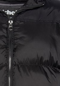 Sort boblejakke med lynlås foran, høj krave, quiltet struktur og glat stof med blank finish.