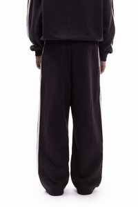 Μαύρο παντελόνι φόρμας με φαρδιά εφαρμογή, με ρίγες στο πλάι σε αντίθετο λευκό χρώμα. Κατασκευασμένο από απαλό υλικό με ομαλή υφή.