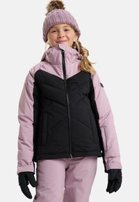 Roze en zwarte geïsoleerde jas met geometrische stiksels, hoge kraag en ritssluiting, gecombineerd met zwarte handschoenen en een gebreide muts.