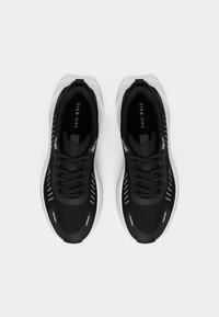 Fekete sportcipők légáteresztő hálós felsőrésszel, fehér talppal és fényvisszaverő részletekkel. Párnázott nyelvet és fűzős kialakítást kínálnak.