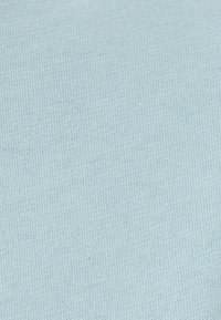 Tejido de punto azul claro con una textura suave y un fino canalé, que presenta una apariencia uniforme sin patrones o acentos visibles.