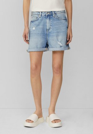 Light blue denim shorts with rolled hems, featuring distressed detailing at the front, complemented by cream slide-on sandals.