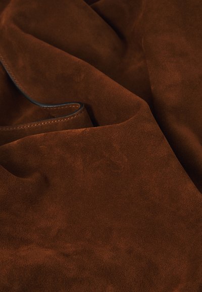 Tissu en daim marron avec une texture douce, une surface lisse et une couleur riche et profonde. Ce matériau tombe délicatement avec un léger éclat.