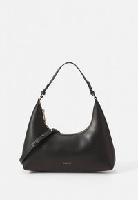 Svart hobo-väska i läder med en böjd form, guldfärgad dragkedja och justerbar rem. Har subtil märkning framtill.