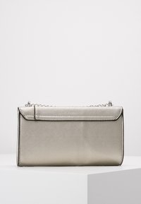 Metaliczna srebrna torba o usztywnionej konstrukcji, z gładką fakturą, zapięciem na zatrzask oraz odpinanym łańcuszkowym paskiem.