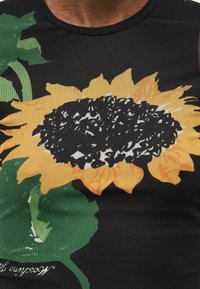 Μαύρο αμάνικο πουκάμισο με μεγάλο τύπωμα ηλίανθου που διαθέτει κίτρινα πέταλα, υφασμένο μαύρο κέντρο και πράσινα φύλλα.