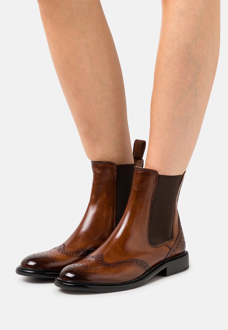 Bottines Chelsea en cuir marron avec des panneaux latéraux élastiques, des détails en brogue sur les orteils et un petit talon. Texture lisse avec une finition brillante.