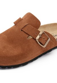 Chaussure en suede marron, à enfiler, avec un bout rond, une sangle réglable et une boucle en métal. Semelle extérieure noire antidérapante avec des détails texturés.