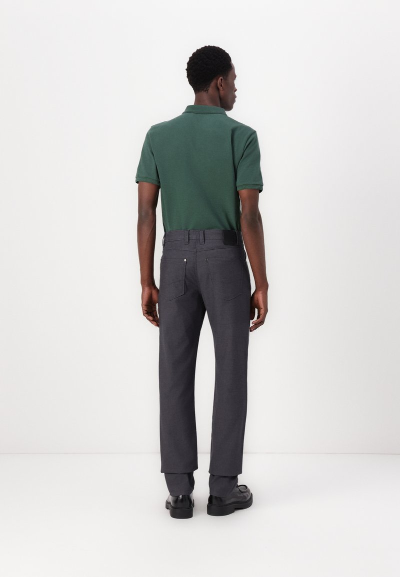 Groene polo met korte mouwen, gecombineerd met donkergrijze broeken. De broeken hebben een rechte snit en een platte tailleband.