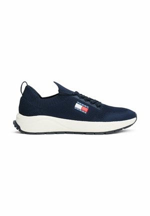 Marine gebreide sneakers met een witte tussenzool en gestructureerde accenten. Heeft platte veters, een lussenlip en een klein logo-patch in rood en blauw.