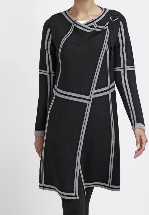 Femme portant une robe noire à manches longues avec des lignes géométriques grises et un panneau avant asymétrique avec un détail anneau en métal sur l'épaule.
