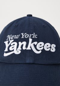 Căciulă din bumbac de culoare bleumarin, cu text brodat "New York Yankees" în alb, design structurat și coroana cu șase panouri.