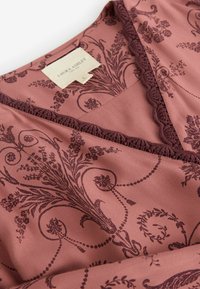Tkanina rožnate barve z cvetličnim vzorcem v temno burgundski barvi, z občutljivo čipkastim robom ob izrezu in oznako "Laura Ashley."