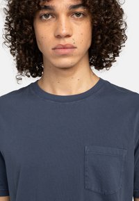 Navyblaue Baumwoll-T-Shirt mit kurzen Ärmeln und einer Brusttasche. Verfügt über einen Rundhalsausschnitt und eine glatte Textur mit minimalen Nähten.