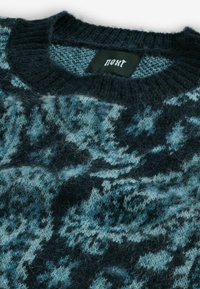 Sötétkék és teal színben kötött pulóver, texturált mintával. Kerek nyakkivágás, puha, bolyhos felület, a márkacímke látható belül.