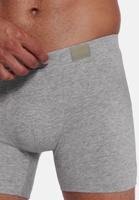 Grau farbene Baumwollboxershorts in enger Passform mit einem bequemen Bund, der ein kleines Logo-Tag in kontrastierender Farbe zeigt.