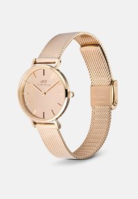 Kuldse võrkköitega kell ümmarguse näo, minimalistliku disaini, nude-dial'i, peenete kuldsete tunni markerite ja turvaliseks kinnitamiseks mõeldud klambriga.