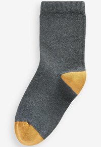 Chaussette grise en matériau texturé, avec un talon et un orteil jaune moutarde contrastants. Design simple avec un revers replié.