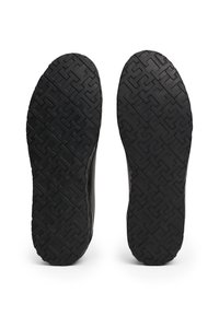 Semelles de chaussures en caoutchouc noir avec un motif géométrique pour une meilleure adhérence. Bords lisses et profil plat sans aucune marque ni logo visible.