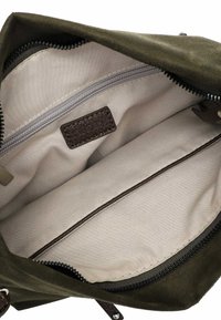 Olive green suede handbag interior with beige lining, a zip pocket, and a brown label embossed "RUE 09." Smooth texture and simple design.
