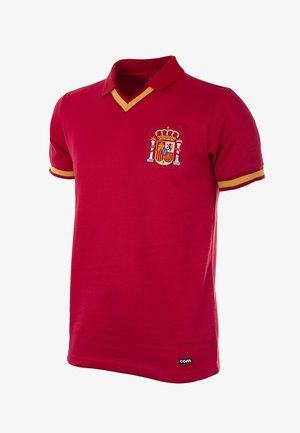 Rode polo met V-hals, gele accenten en een geborduurd wapenschild op de linkerkant van de borst. Zachte stof met korte mouwen.