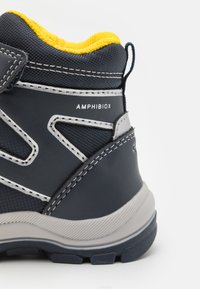 Bota de senderismo de color navy con material sintético texturizado, cuello acolchado amarillo, acentos grises y el logo "AMPHIBIOX" en el lateral.