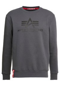 Sudadera gris con cuello redondo, que presenta un logo negro impreso y texto. Incluye una etiqueta de tela roja en el dobladillo. Material suave y grueso.
