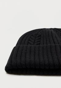 Mustat neulottu pipo, jossa on ribbipinta ja palmikkoneulekuvioita, taitettu alareunasta lisälämmön ja tyylin vuoksi.