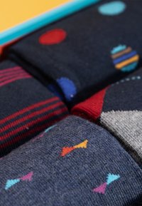 Set di calze con colori scuri, trame e motivi: pois rossi, righe e frecce multicolori su uno sfondo blu navy.