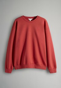Sudadera roja de tejido suave con cuello redondo y mangas largas. Presenta puños y dobladillo acanalados, con un ajuste relajado.