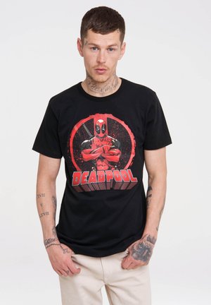 Black cotton t-shirt featuring a large red and black graphic of Deadpool, including his iconic mask and crossed weapons, with bold text.