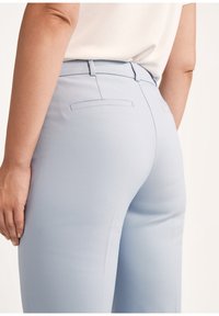 Jasnoniebieskie spodni skrojone na miarę o gładkiej fakturze, z klasycznym pasem, szlufkami na pasek i dwiema tylnymi kieszeniami.