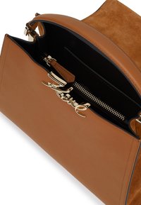 Brązowa skórzana torebka z logo w kolorze złotym, z zamkiem błyskawicznym, zamszowym wnętrzem i sztywną konstrukcją. Teksturowane wykończenie na klapce.