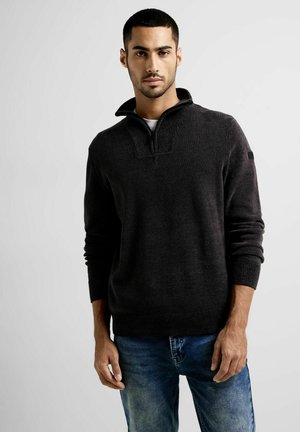 Suéter de tiro oscuro con diseño de cuello con cremallera, puños y bajo de canalé. Fabricado con una tela suave, presenta una textura sutil y un corte relajado.