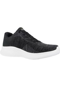 Zapatilla deportiva negra con parte superior de tela texturizada, cierre con cordones y suela blanca acolchada. Cuenta con un logo en la lengüeta y acentos en contraste.