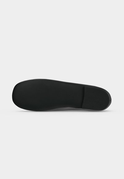 Semelle de chaussure noire avec une surface lisse et plate et une section de talon rectangulaire, présentée sur un fond clair uni.