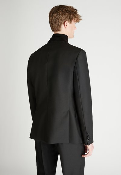 Zwarte op maat gemaakte blazer met een hoge kraag, gestructureerde schouders en een soepele textuur. Voorzien van knopen op de manchetten en een strak, minimalistisch ontwerp.