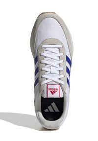 Białe sportowe buty z niebieskimi paskami i szarym zamszowym noskiem. Posiadają białe sznurowadła i czerwoną metkę z logo na języku. Czarna podeszwa.