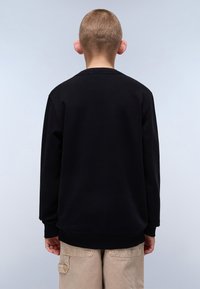 Svart hettegenser med lange ermer og rund hals, laget av myk stoff. Vist fra baksiden, med ribbestrikkede mansjetter og nederkant.