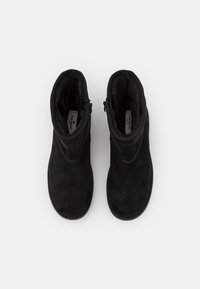 Bottines noires en daim avec une finition texturée, dotées de fermetures éclair sur les côtés et d'un design à bout rond. Doublure intérieure lisse.