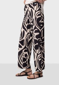 Pantalons à jambes larges avec un motif abstrait noir et beige, fabriqués en tissu léger avec une taille élastique et des poches latérales.