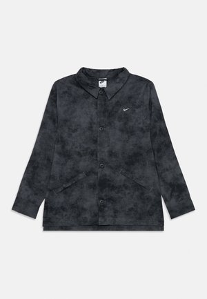 La veste en denim noire possède un devant boutonné, un col pointu, deux poches avant et un petit logo blanc sur la poitrine.