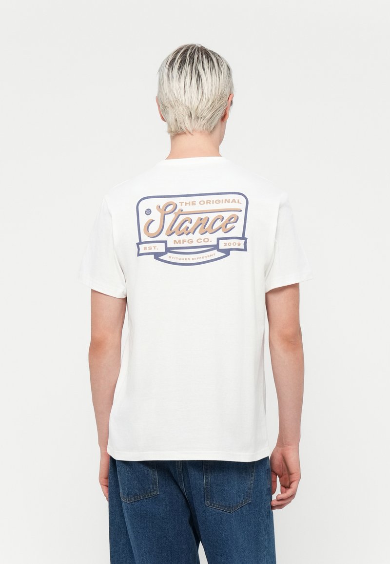 Weißes Baumwoll-T-Shirt mit einem bunten Grafikdruck auf dem Rücken, mit rundem Halsausschnitt und kurzen Ärmeln, vor einem neutralen Hintergrund präsentiert.
