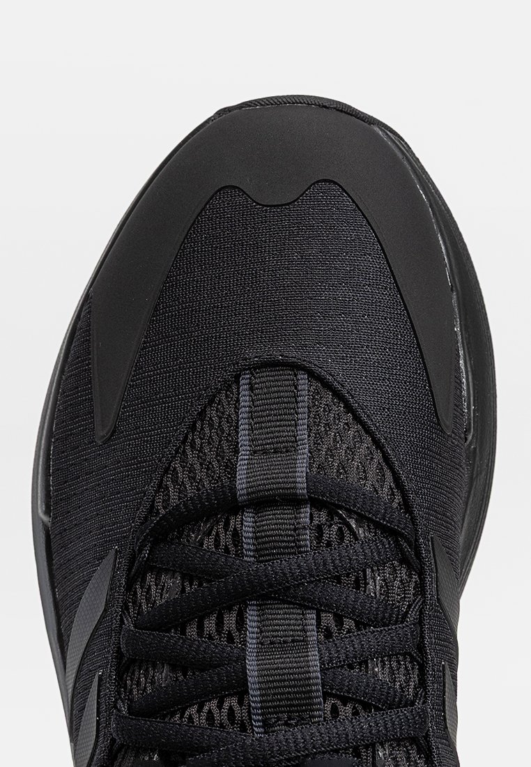 Zapato deportivo negro con parte superior de malla y paneles texturizados, cordones planos y una puntera de goma reforzada. Acabado con un diseño de tres franjas.