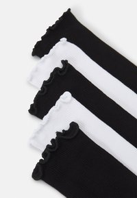 Ribbed socks in black and white, featuring ruffled top edges. Four pairs displayed, alternating colors vertically.