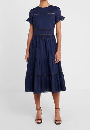 Vestido azul marino en capas con mangas cortas con volantes, bandas horizontales decorativas y longitud hasta debajo de la rodilla. Hecho de tela ligera.