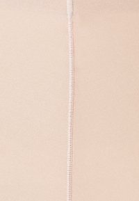 Naadloos nude weefsel, gladde textuur, met een centrale stiknaad. Het totale oppervlak is gelijkmatig met een lichte glans.